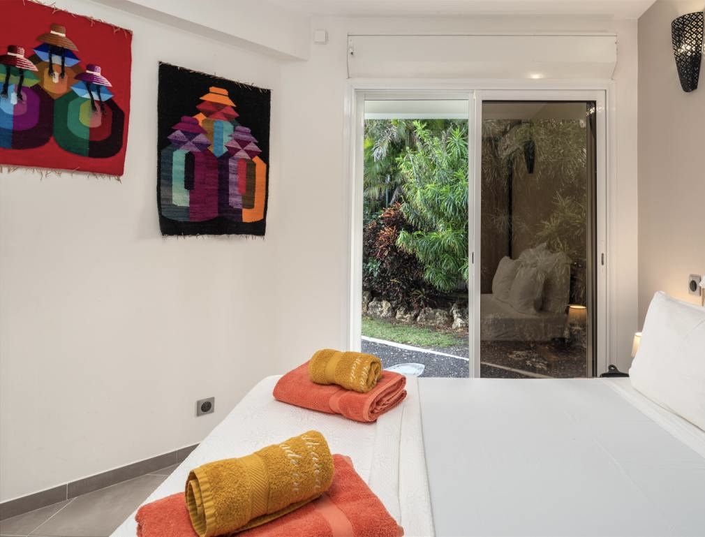 Chambre décorée de tentures artisanales colorées ouvrant sur la végétation