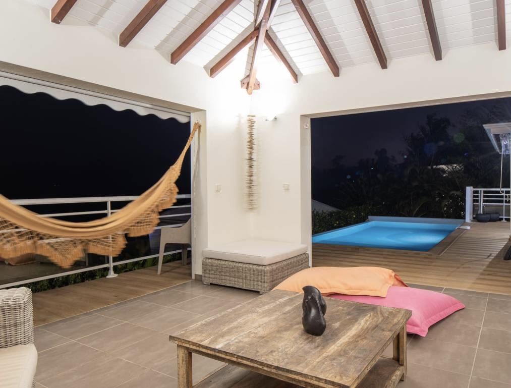 Salon extérieur avec hamac face à la piscine de nuit